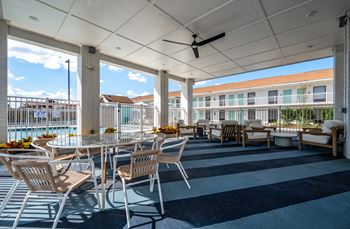 A patio with chairs and a table is covered by a white roof.